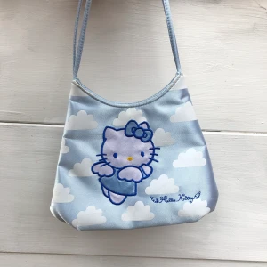 Hello Kitty Axelväska 🦋 - Supersöt, ljusblå axelväska med hello kitty på! Snygg detalj till outfitten där mobil och lite småsaker får plats.😁 frakt tillkommer eller så kan jag mötas i sthlm. 💟