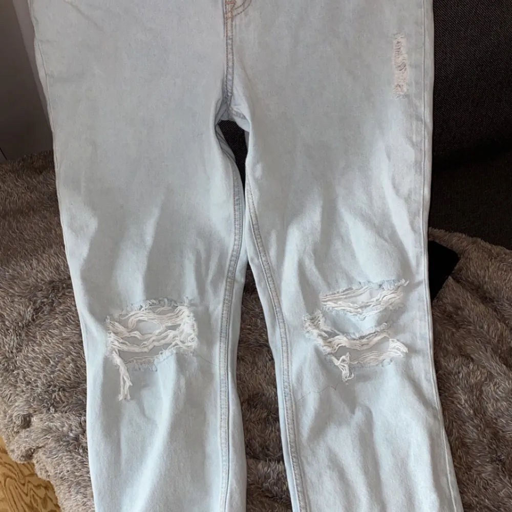 Ett par ljusblåa jeans med slitage på knäna och hög midja  oanvända jeans! . Jeans & Byxor.