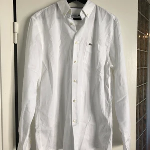 Lacoste  - Fin vit Lacoste herrskjorta. Modellen Classic fit. Passar även för dam. Jag själv har använt den och jag är kvinna. Nypris 999. Nyskick.