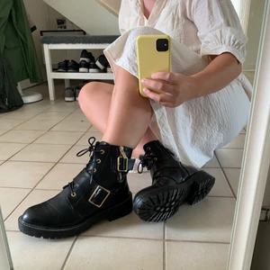 Svarta kängor / boots med guld  - Använda en gång, säljs pga för små. Dragkedja på insidan för att kunna sätta på skorna. Dragkedjan funkar bra. Går även att justera skorna med snören fram på skon. Skorna är köpta på ASOS. Du står för ev frakt (: