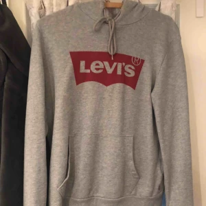  - Grå hoodie med levis tryck. Använd ett fåtal gånger och är i super skick. Storlek S men passar en M också. 
