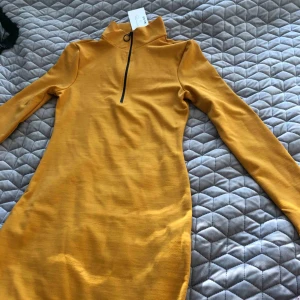  - En tajt klänning som har en dragkedja vid halsen, helt oanvänt och prislapp kvar.