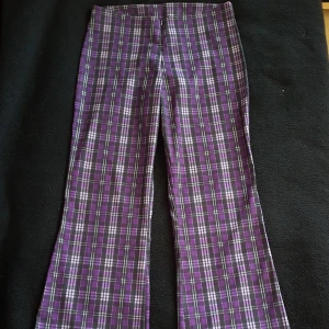 Vintage rutiga byxor - Vintage lila rutiga byxor i storlek M. I fint skick, lite skavd på hänget på drakjedan vad jag kan se. Fraktkostnad blir 67kr.