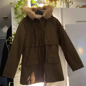 Fin parkas med lappen kvar i en mörkgrön färg som inte riktigt gör sig rättvis på bild. Äkta pälskrage som är avtagbar och teddymaterial på insidan