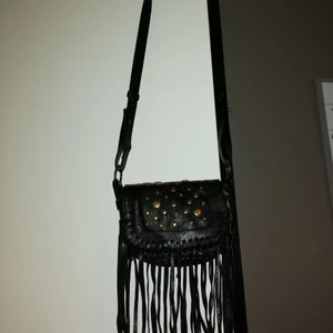 Svart skinnväska med nitar - Liten väska i fuskskinn med nitar och fransar. Tar swish eller kontanter (vid möte i malmö). Leverans betalas av köparen