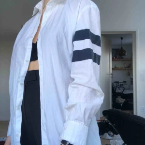  - Snitsnygg vit skjorta med marinblåa ränder på ärmarna. Använd en del men fortfarande i bra skick!
