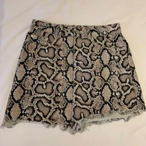 Ormskinnsmönstard jeanskjol från Zara - Jättefin ormskinsmönstrad jeanskjol från Zara i nyskick, endast använd en gång. Kjolen är i storlek M och inköpspriset var 250kr. Köparen står för frakt.