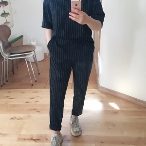 Mörkblått set i strl 34  - Mörkblått set med tunna vita ränder i strl 34. Sparsamt använd och nästintill nyskick!! Svalt, ordentligt tyg och med stretch i midjan på byxorna. Polyester 95% Elastan 4% Viscose 1%. FRAKT INKLUDERAT