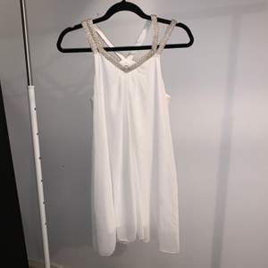En vit klänning från CLUBL, köpt för längesen och är knappt använd. Axelbanden har vita och silvriga pärlor på sig. Klänningen passar både s och m 