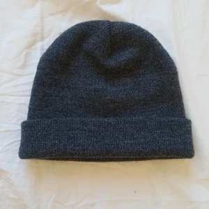  - Mössa i grått. Stickat material. Frakt: 35kr