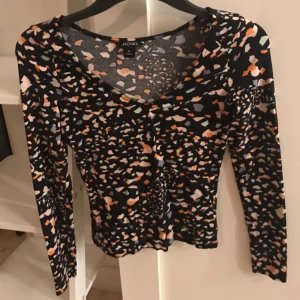  - Monki topp multifärgad med svart botten, långärmad v-ringad i bomull storlek XS, kortare i modellen 