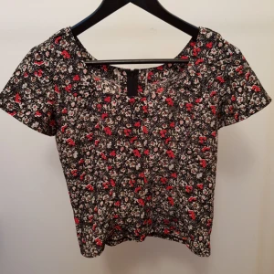 Blommig topp  - Söt blommig topp med dragkedja på ryggen, säljes pga av jag aldrig använder den, nyskick. Kan mötas i tc eller fraktas. 