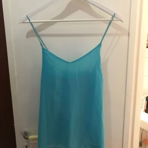  - Oanvänt turkost linne, lös passform med fint kors i ryggen av banden.