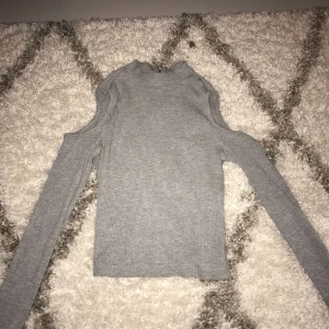  - En grå, ribbad tröja med hål för axlarna. Vid ryggen finns det en dragkedja. Jag tror det är en XS men jag som har S har använt den och då sitter den jättefint, dock aningen kort kanske. Superbra skick men säljes då den inte är min stil längre 