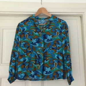  - Vintageblus med 60-talsmönster. Litet hål som är lätt att sy igen på vänster axel (se bild 3). Annars väldigt fin kvalitet!