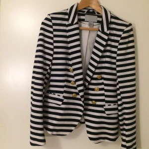  - Fin svart, vit med guldiga knappar kavaj, figursydd. 