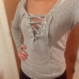  - Ljusgrå topp från Ginatricot. Snörning framtill som kan justeras efter önskemål. Storlek XS. Priset kan diskuteras vid snabb affär! Köparen står för frakt kostnaden🌸