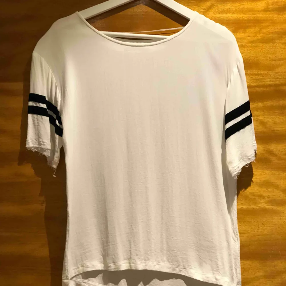 Supersnygg T-shirt med ”fladdrigt” material, slitningar vid armar. Storlek 36. Från Design Only . T-shirts.