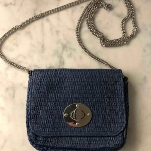  - Liten väska i blått med kedja som kan bäras crossbody