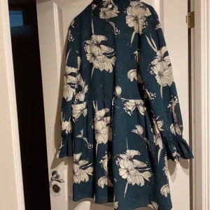 Klänning från Vila i strl L - Fin klänning med blommigt tryck och hög krage i strl L. Använd ett år gånger och i ett mycket bra skick. Köparen betalar frakt.