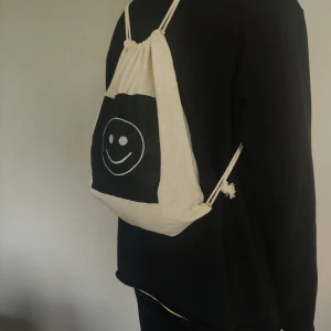 Moody Drawstring Bag  - Visa alla i din omgivning vilket humör du är på med denna dubbelsidiga gympapåsen. ♻️ Fraktkostnad på 22kr tillkommer. ✨