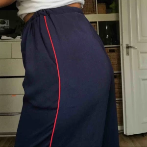  - Otroligt snygga flowy marinblå byxor med en röd rand längs sidorna på benen. Endast använda 1 gång!