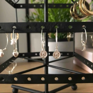  - 4 par silvriga örhängen med små berlocker på. Aldrig använda.