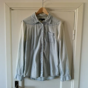  - Ljus jeansskjorta med knappar i pärlemo. 
