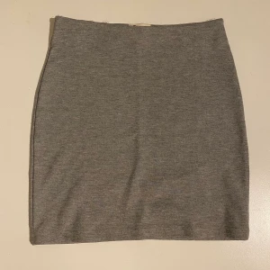 Kort tajt kjol - grå - Köpt för några år sedan, använt skick, men syns inte utåt. Lite små (ej synliga) noppror. Lite trådar - se sista bilden. Kan skicka fler bilder om så önskas, men märks knappt 🤍 Grå vanlig kort kjol, perfekt basicplagg!! Resår i midjan, lite stretchig som formas efter kroppen 🤍 FRI FRAKT