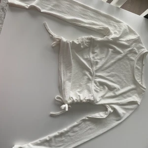 Långärmad vit tröja - Skön långärmad vit tröja. Använd en gång. Säljer pågrund av att jag tappade i tredje för den. Lapparna är borttagna pga obekväma. Men annars en väldigt fin tröja. Band vid sidan som man kan dra åt för att framhäva midjan. Frakt diskuteras❤️