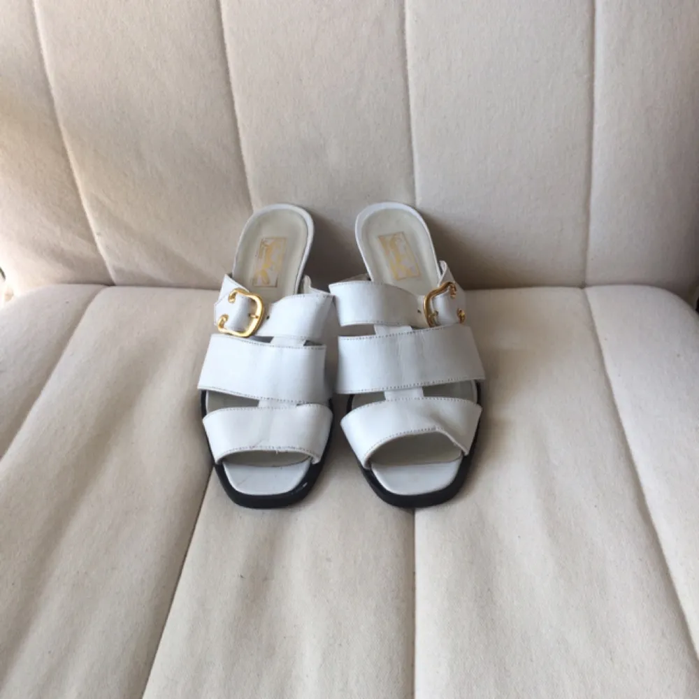 White leather imitation slip-ins with golden buckle on the side. Low heel, comfortable to walk in. Fits small 37. Note: inner side of left heel has a black mark that can be removed. Hence the low price. . Skor.
