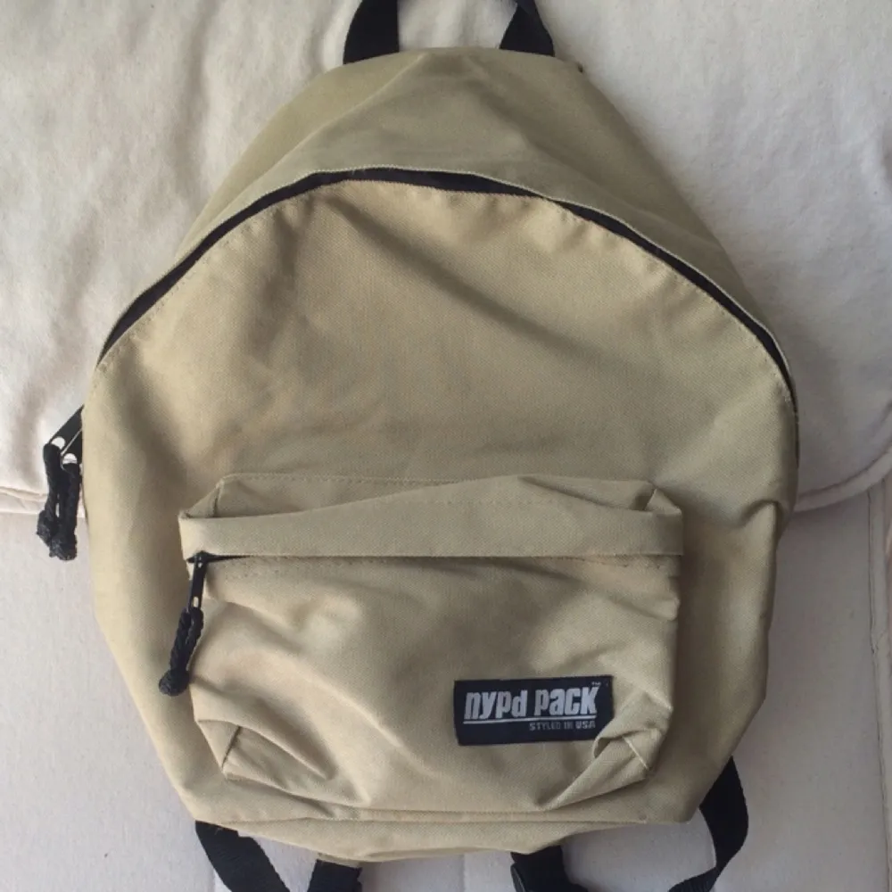 Vintage beige mini backpack from NYPD Pack with small pocket in front. Adjustable straps of handing low or high. Sparsely used and kept stored. . Väskor.
