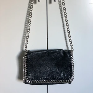 Svart kedjeväska från Tiamo - Svart väska från Tiamo. Fint skick använd endast ett fåtal gånger. Stängs med dragkedja och magneter. Förutom innefacken på bilden finns det även ett dragkedjefack på baksidan av väskan. Köpt för: 500 kr. Jag säljer min för 90 + frakt, alltså 153 kr. Pris kan diskuteras