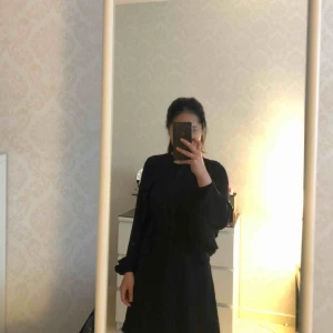  - Svart klänning med öppet rygg.