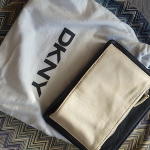  - Svart/vit läder clutch från DKNY, lite slitage.  Köparen står för frakt  Betalning via swish 