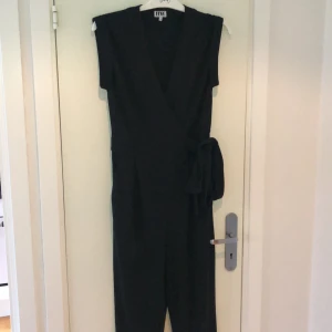 Make Way byxdress strl M - Svart byxdress i skönt material. V-ringad med spänne på sidan. Använd ett fåtal gånger och i fint skick. 