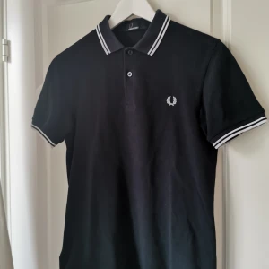 FRED PERRY PIKÉ  - Köpt förra sommaren, fin kvalité men i använt skick. Reserv knappen är påsydd i kragen. Nypris 800kr, säljer för 250kr