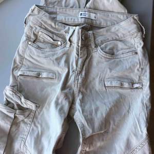 Ett par lågmidjade beigha  jeans med ficka på ena låret. ifrån Gina tricot. Oanvända. Köpta för 499kr med säljer för 120kr. Pris kan diskuteras!
