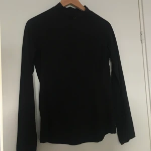 Ridtröja - En figursydd ridtröja som passar perfekt att  ha under varmare kläder eller bara som den är! Hög i nacken med en fin liten hästsko som detalj. Luktar absolut inte häst! Från märket CRW och är i storleken xs. 