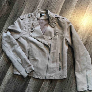  - Kort beige jacka med 2 olika knäppningar/urringningar i halsen. Som ny. Köparen står för porto