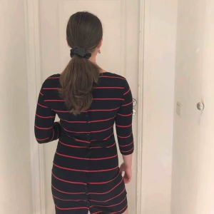  - En mörkblå/ röd randig klänning från Svea med knäppningar på baksidan 