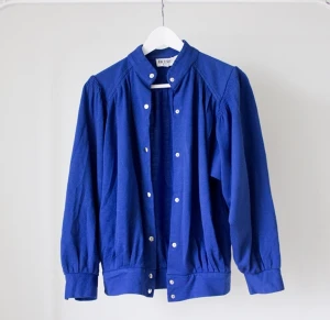  - Blå jacka/kofta med tryckknäppning. 70% akryl, 30% ull. Kliar inte! Köpt i vintagebutik. Bra skick utan synliga skavanker. Unisex. Perfekt festival- och sommarjacka!