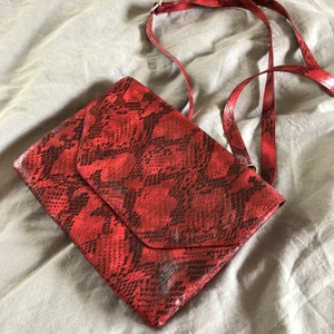 Väska Monki - Felfritt skick. Får plats med ORIMLIGT mycket för en sån liten väska. Rött snakeprint. Justerbart band. Finns ej hos Monki längre. Frakt ingår