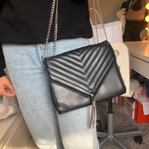 Väska - Axelväska med kedja och en liten tofs☺️ den är i läder imitation och väldigt sparsamt använd