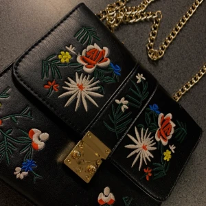 broderad handväska  - jättesöt fake läder handväska med broderade blommor! Lång guldkedja som axelrem, säljes då den inte kommer till användning 💕 