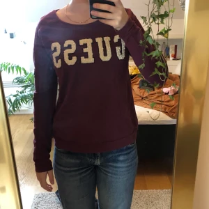 Vinröd guesströja - Lite tjockare tröja från Guess. Fina pärlor i texten. Oklart vilken storlek men skulle slänga XS-S.