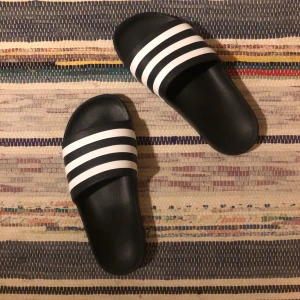 Adidas-tofflor - Ett par oanvända svart/vita adidastofflor i storlek 38, säljes för att de är för små✨ frakt tillkommer