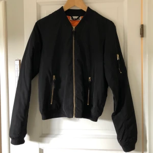 Bomberjacka  - Snygg bomberjacka som passar perfekt till hösten. Guldiga dragkedjor och orange quiltat foder. Bra skick. Strl S