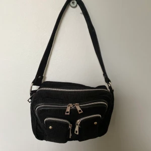 Nunoo väska - Säljer nu min älskade nunoo väska. Använd, men jättebra skick, endast lite sliten färg på löparna på en av dragkedjorna. Väldigt snyggt manchestermaterial och rymligare än man kan tro, samt många fack. Köptes för 899 kr