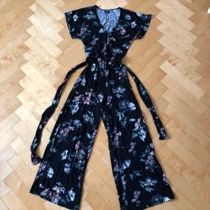 Byxdress  - En superbekväm och fin byxdress. V-ringad, midjeband och fladdriga ben. Kan räkna på en hand hur många gånger den är använd och den är därmed i fint skick. Perfekt som den är eller med en tröja över i kallare väder🥰🍂